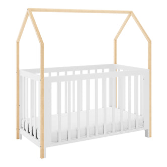 Damaris Solid Pine Baby Cot Bed in white and natural wood, featuring a house-shaped frame with slatted sides, and a mattress inside, blending style and functionality for a cosy nursery space.