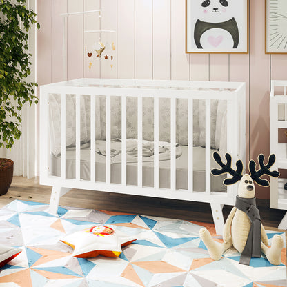 Eudora Classic Solid Wood Baby Cot in White with adjustable heights, features crisp lines, and pale-grey patterned bumpers, surrounded by modern nursery decor including a geometric rug and hanging mobile.
