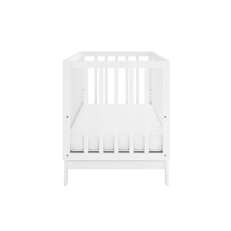 Eudora Classic Solid Pine Adjustable Nursery Cot – White, featuring a front view of a white wooden crib with slatted sides and fitted mattress, showcasing its sturdy pine construction and adjustable mattress base.