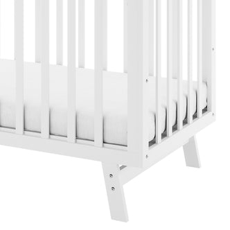 Close-up of Eudora Classic Solid Pine Adjustable Nursery Cot – White, showcasing slatted side panels, mattress, and angled leg. Highlights clean lines and sturdy pine construction for a timeless nursery piece.