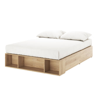 Eulalia Double Storage Platform Bed Base with Drawer in Oak features a light oak low wooden frame, white mattress, two pillows, and open storage cubbies at the foot for practical elegance.