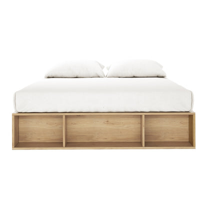 Eulalia Queen Storage Platform Bed Base with Drawer in Oak featuring a light-wood frame, three open cubby shelves at the footboard, topped with a low-profile white mattress and duvet.