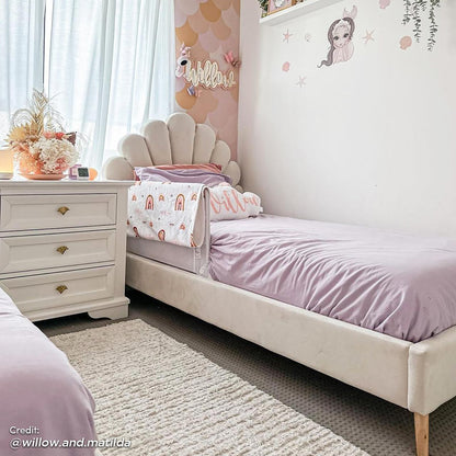 Fayette Kids Single Velvet Fabric Bed Frame in Cream White, featuring a scalloped seashell headboard, lavender bedding, and under-bed storage, creating a cozy, magical retreat in a pastel-themed children's room.