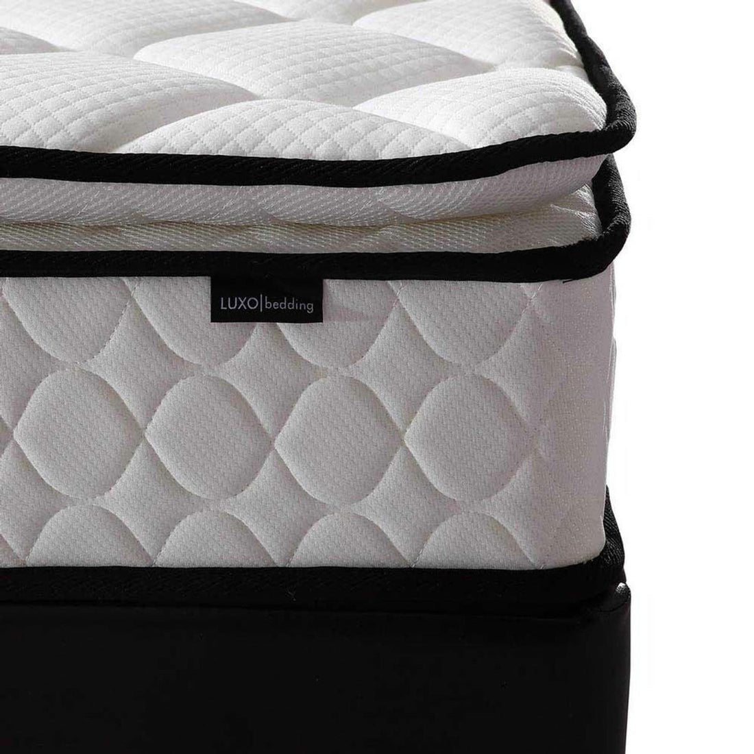 Close-up of Venus Mattress from Aristos & Venus Bunk Bed & Mattress Package, featuring a quilted white cover with raised pattern, black piping, and LUXO bedding tag, resting on a black foundation.