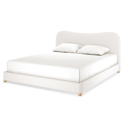 Ginnie Bouclé Curved King Bed Frame - Cream White features a low-profile design with an off-white fabric, gently curved headboard, fitted mattress, matching pillows, and round wooden feet, exuding elegance and comfort.