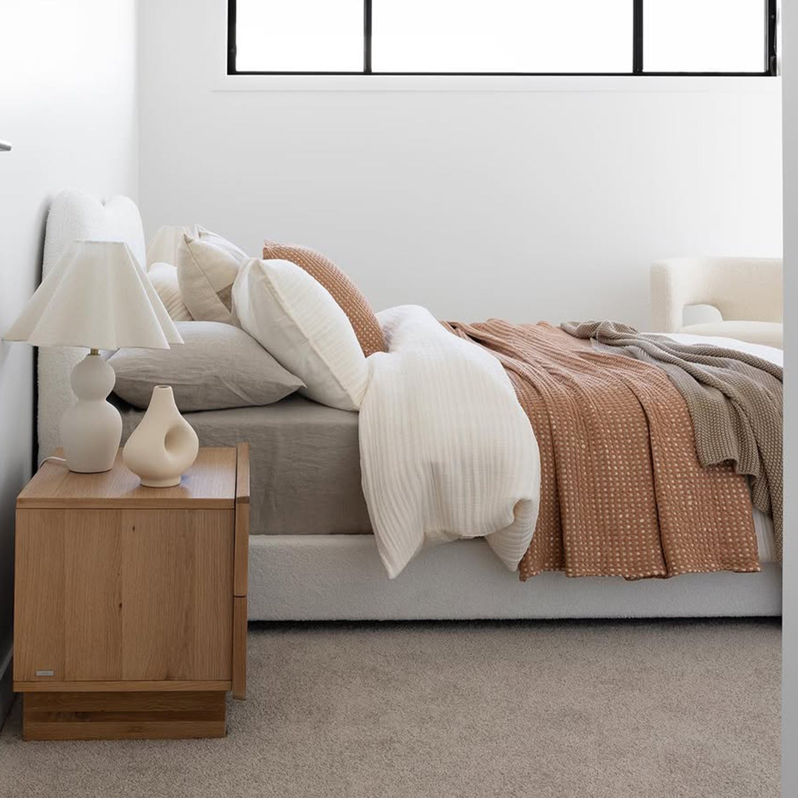 Ginnie Queen Curved Bouclé Cloud Bed Frame in Cream White, featuring a plush curved headboard and elegant bouclé fabric, set in a minimalist bedroom with neutral linens and a light taupe carpet.