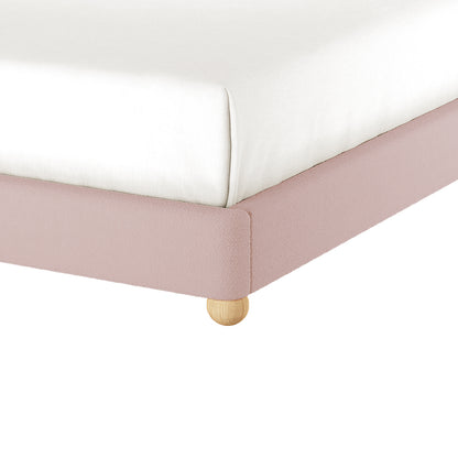 Ginnie Queen Curved Bouclé Cloud Bed Frame in Pink, showcasing a white mattress on a low, pale-pink upholstered platform with a small round wooden leg, highlighting its modern, elegant design.