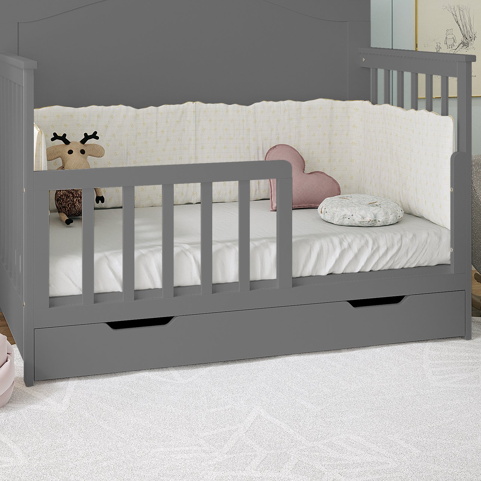 Giro Solid Pine Toddler Bed Rail Kit in Grey shown as a daybed/crib with low front rail, full side rails, pull-out drawer, white sheet, bumper, plush deer, heart cushion, and bolster pillow.