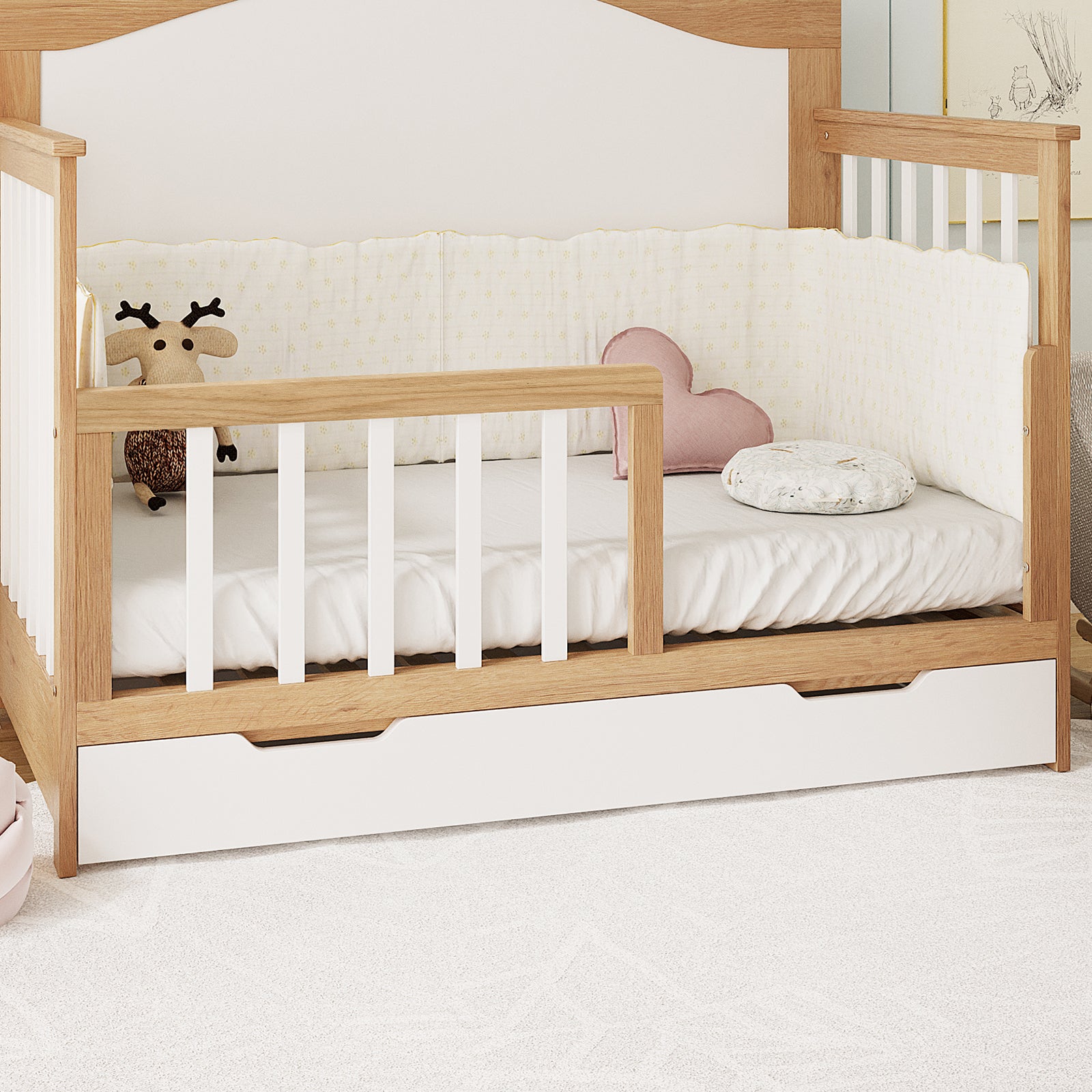 Giro Solid Pine Toddler Bed Rail Kit in Walnut Tone, featuring a light wood frame with white slatted sides, plush deer toy, pink heart pillow, and marbled cushion on a white mattress.