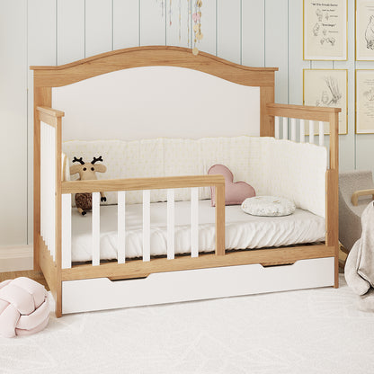 Giro Solid Pine Toddler Bed Rail Kit in White Natural, featuring a light oak-tone frame and white slatted sides, with a low front rail and pull-out drawer, styled like a convertible crib.