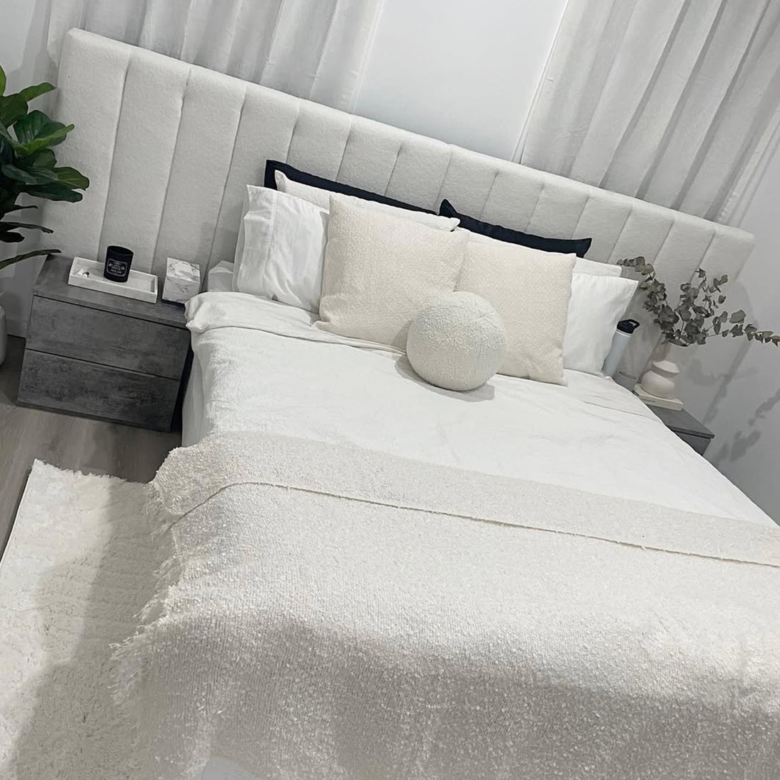 Aquila King Extra Wide Bouclé Headboard in Cream White features vertical channel tufting and luxurious bouclé fabric, complementing crisp white bedding and textured cream pillows for a serene, minimalist bedroom ambiance.