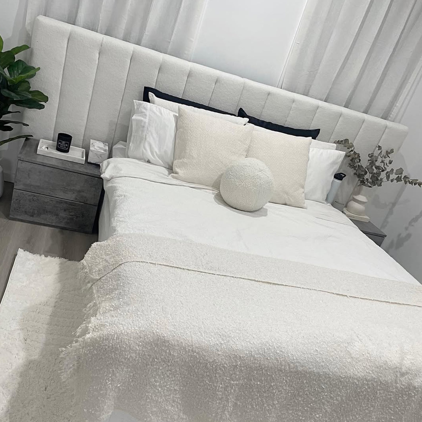 Aquila King Extra Wide Bouclé Headboard in Cream White features vertical channel tufting and luxurious bouclé fabric, complementing crisp white bedding and textured cream pillows for a serene, minimalist bedroom ambiance.