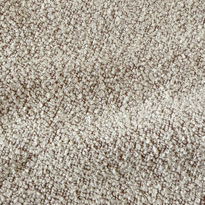 Close-up of warm beige boucle fabric texture with woven looped yarn pattern