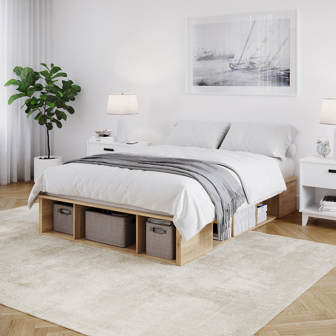 Herais Double Platform Bed Base with Storage in Oak features a low wooden platform, built-in cubbies with bins and books, white linens, and a light gray throw, complemented by matching nightstands and a seascape print.