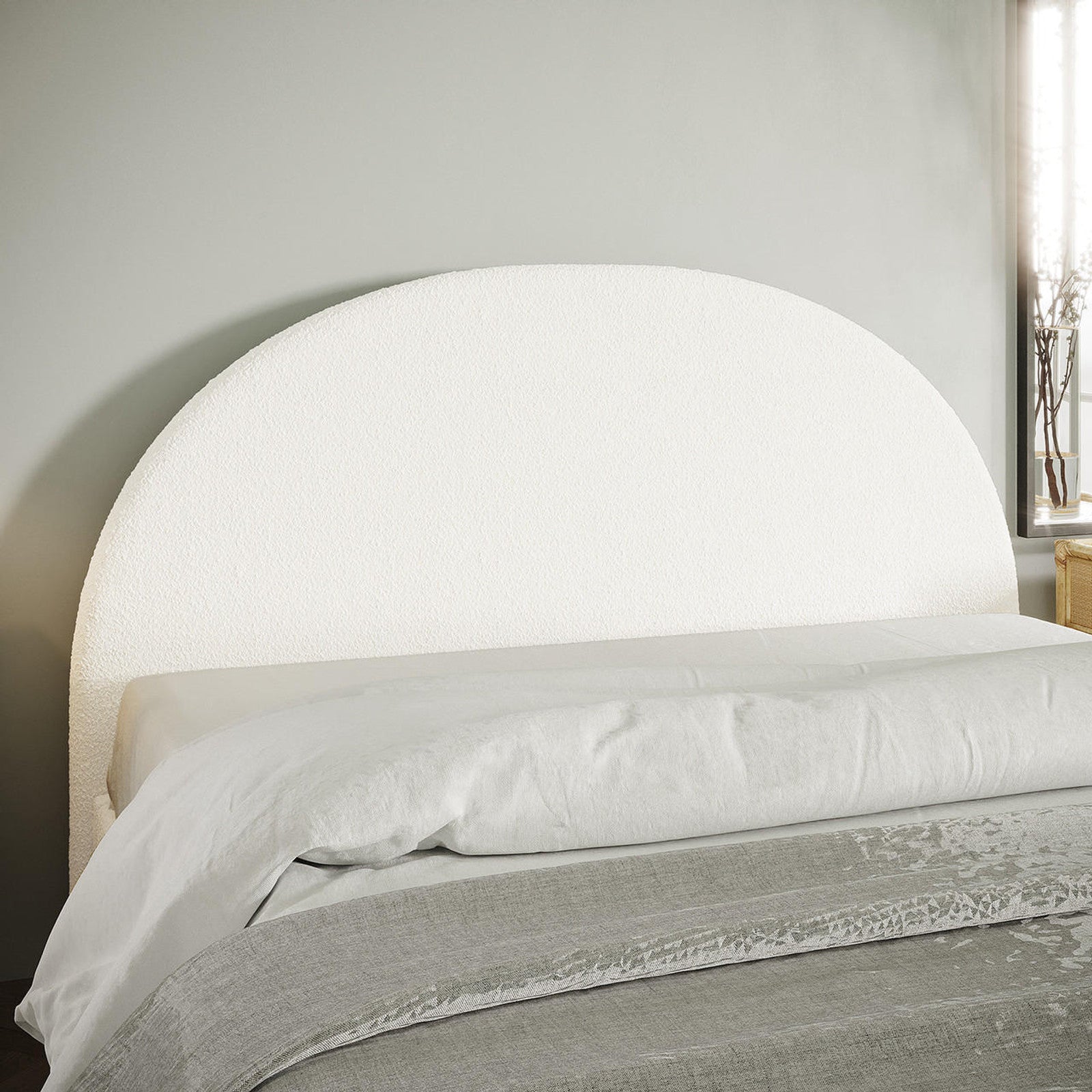 Florus Bouclé Double Upholstered Round Bed Headboard - Cream White features a textured half-circle design. Positioned against a pale gray wall, it complements crisp linens and a light gray coverlet for a modern aesthetic.
