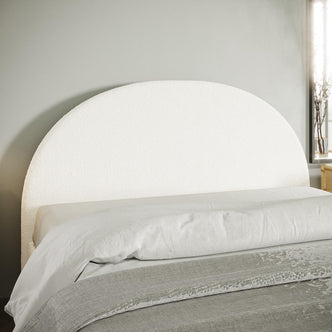 Florus Bouclé Double Upholstered Round Bed Headboard - Cream White features a textured half-circle design. Positioned against a pale gray wall, it complements crisp linens and a light gray coverlet for a modern aesthetic.