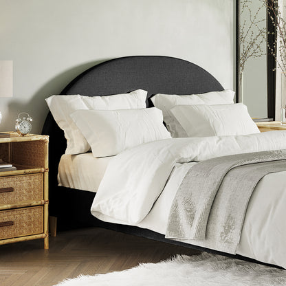 Florus Queen Arched Bouclé Fabric Headboard in Black features prominently with its curved silhouette and plush upholstery, set against a backdrop of crisp white bedding and a stylishly arranged bedroom corner.