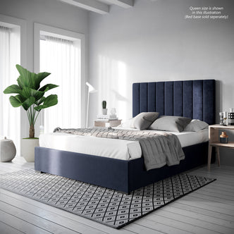 Gratiana Upholstered Velvet Queen Headboard features a plush, curved design with detailed stitching, freestanding against a bed with a blue headboard, highlighted by its luxurious texture and elegant form.