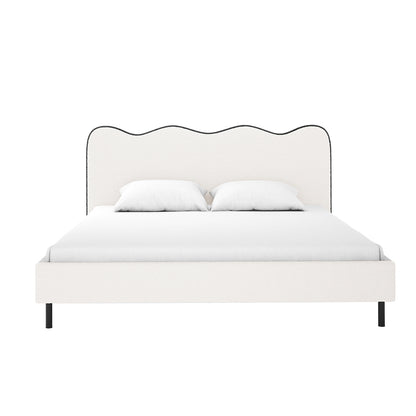 Kaylie Queen Boucle Fabric Bed Frame in White & Black features a wave-shaped headboard in off-white boucle with black trim, white bedding, and black metal legs for a modern, elegant look.