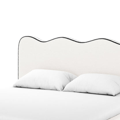 Kaylie Queen Boucle Fabric Bed Frame in White & Black features a wavy upholstered headboard with contrasting trim, white bedding, and pillows, creating a minimal, monochromatic aesthetic against a plain background.