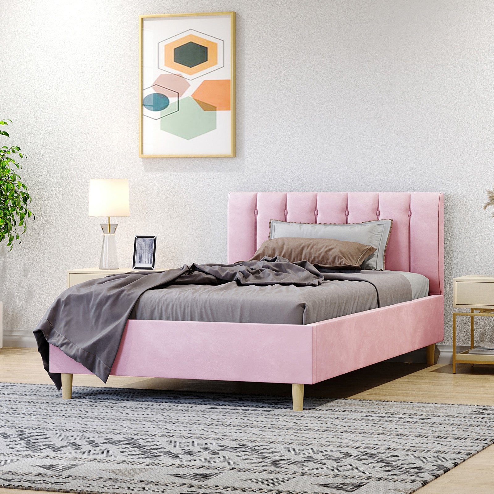 Kelly King Single Velvet Fabric Bed Frame in Pink with a vertically tufted headboard, accompanied by gray bedding and accent pillows, situated beside stylish nightstands and a framed abstract print above.