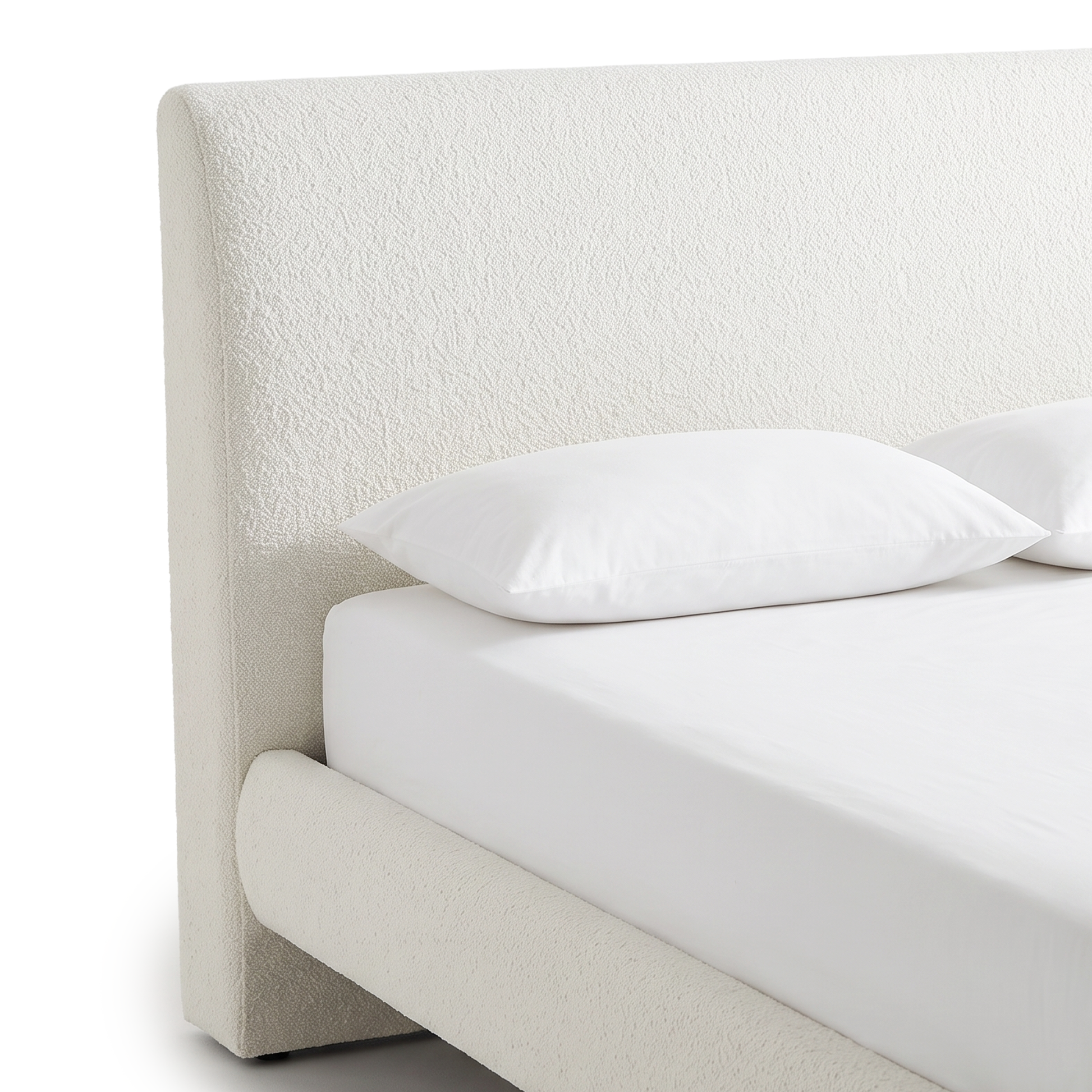 A close-up view of the white bouclé headboard and upholstered side rail of a modern bed frame with white bedding on a white background.