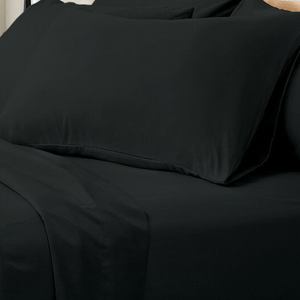 Valeria 1000TC Ultra Soft Bed Sheet Set Super King – Black displayed on a bed, highlighting its luxurious, smooth texture and elegant appearance, with a person sitting nearby on a couch.