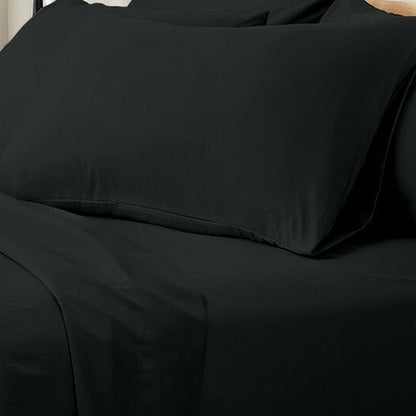 Valeria 1000TC Ultra Soft Bed Sheet Set Super King – Black displayed on a bed, highlighting its luxurious, smooth texture and elegant appearance, with a person sitting nearby on a couch.
