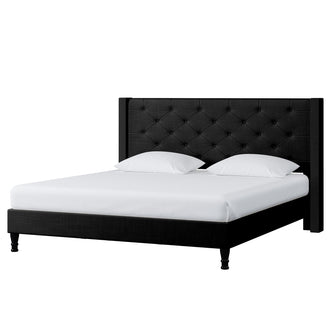 Maggie King Winged Fabric Bed Frame – Black features a prominent Chesterfield-style headboard, deep-buttoned upholstery, and robust construction, showcased on a bed with white pillows and sheets.