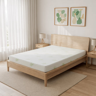 Junior Single 15cm Foam Mattress in Medium Firm rests on a minimalist wooden platform bed, featuring a subtle leaf-patterned cover. The setup includes matching nightstands, abstract wall art, and sheer curtains.
