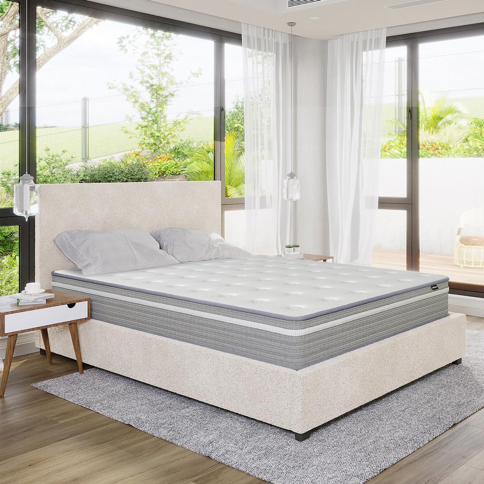Oriona Queen 25cm Pocket Spring Gel Mattress in Medium Firm, displayed on a low-profile upholstered bed, with tufted surface and two pillows, set in a bright, minimalist bedroom.