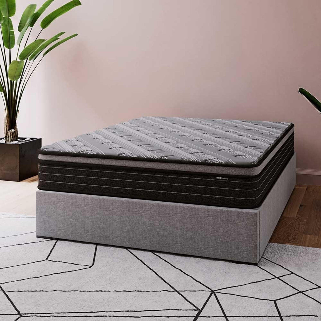 Phoebe Queen 33cm Euro Pillow Top Pocket Spring Mattress shown on a low gray bed base; features a dark gray top and black midsection, complemented by a geometric-patterned rug and greenery for a modern bedroom look.