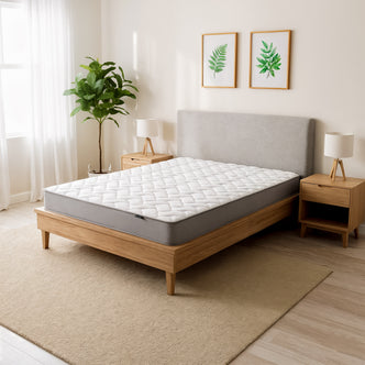 The Vesta Single 20cm Pocket Spring Latex Mattress in Medium Firm is shown on a light-wood bed frame. It features a white quilt-top and is part of a minimalist bedroom setup with botanical prints above.