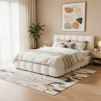 Nikias Queen Bouclé Fabric Bed Frame in Cream White, featuring a plush tufted headboard and base, set in a modern bedroom with abstract art, sheer curtains, and a wooden nightstand.