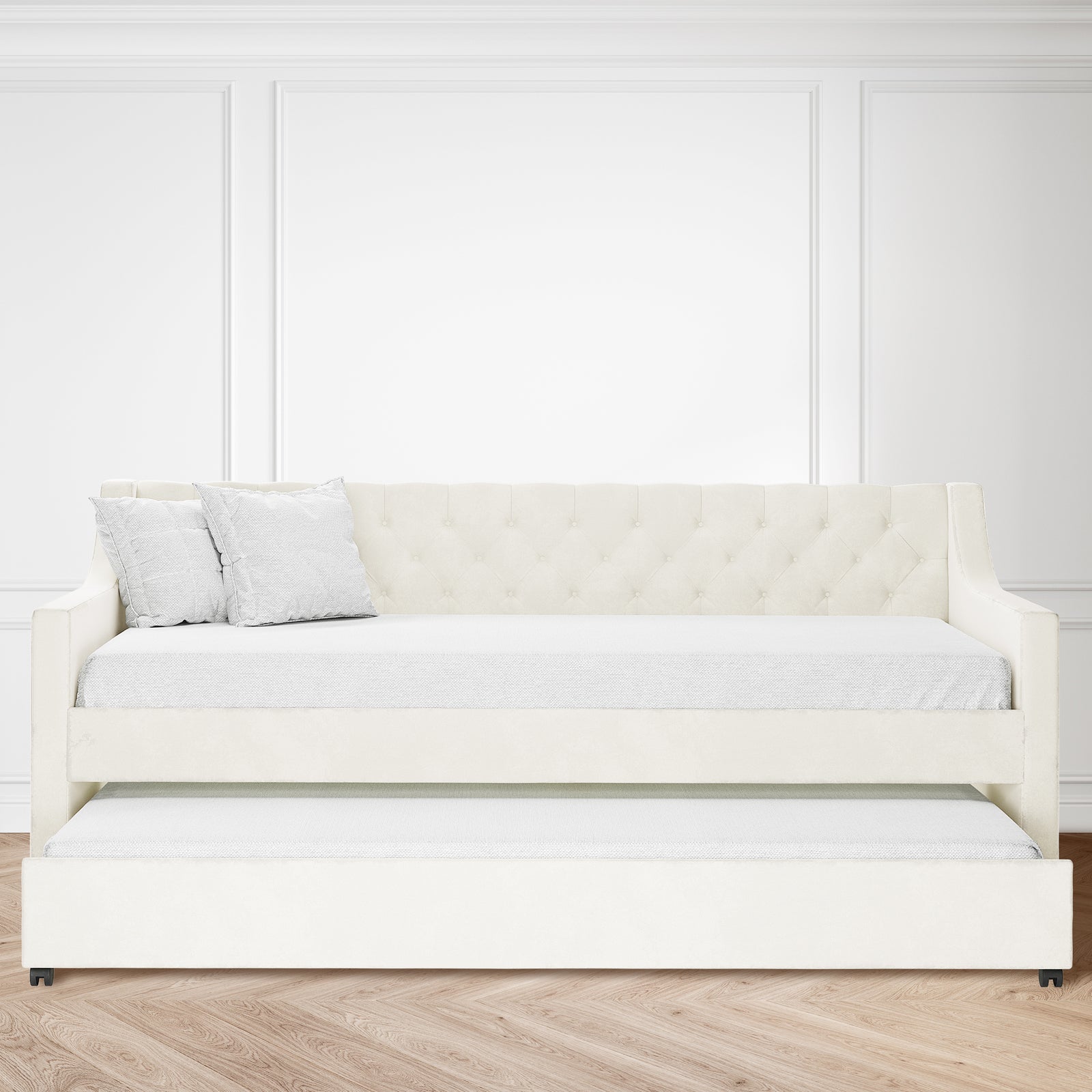 Ovidia Velvet Single Sofa Daybed with Trundle in Cream White, featuring tufted backrest and two throw pillows, set against white paneled walls and light herringbone wood floor, showcasing elegance and functionality.