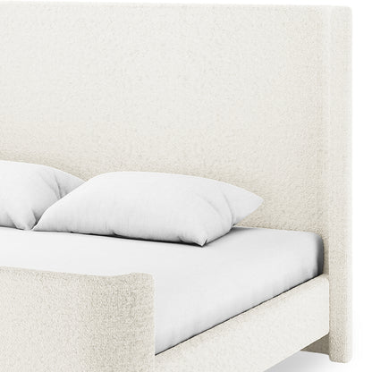 Palmira King Boucle Fabric Bed Frame in Cream White, featuring a sleigh design with plush headboard and footboard, upholstered in textured fabric, complemented by a simple fitted sheet and pillows.