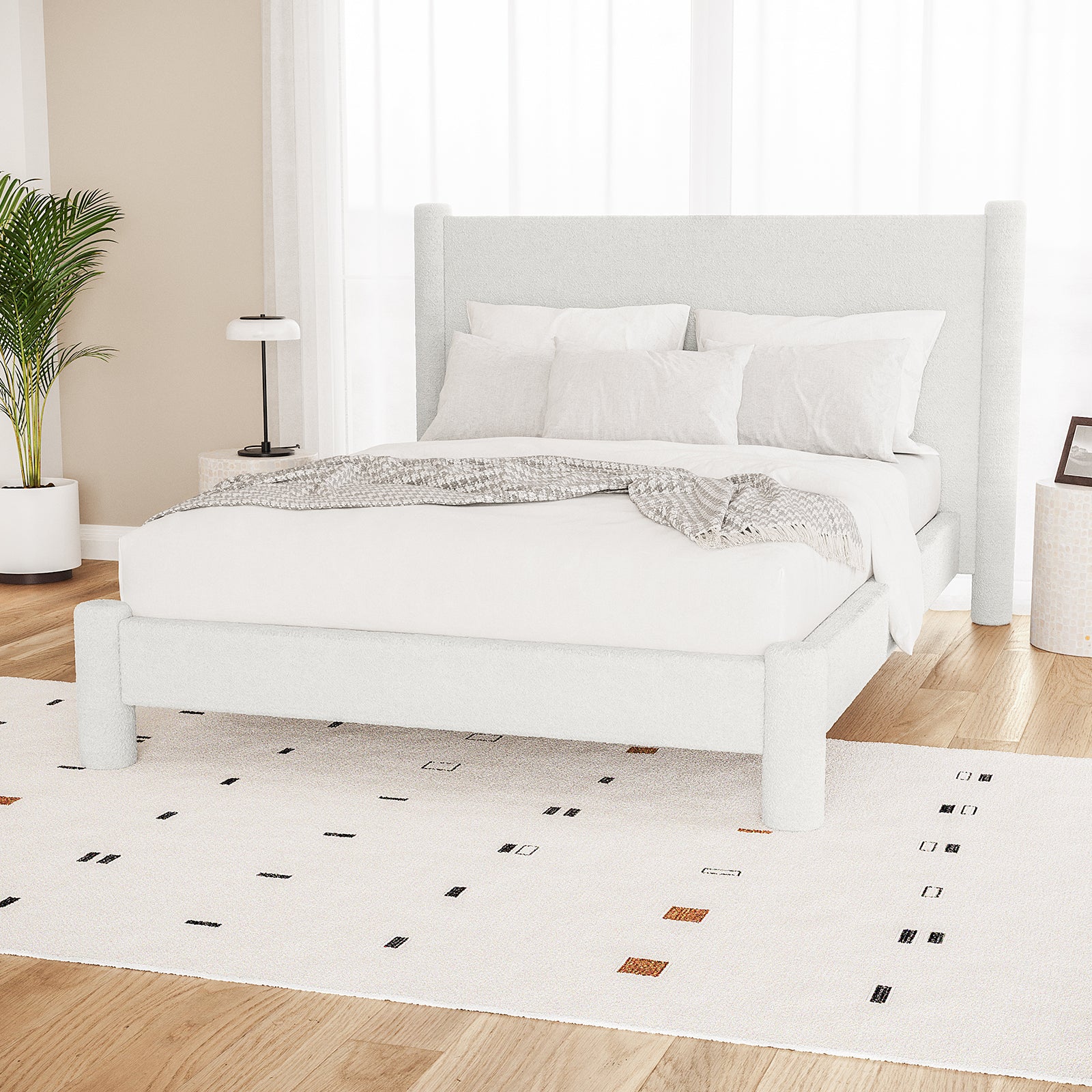 Rhoda Double Boucle Fabric Bed Frame in Cream White, featuring an oversized curved headboard and low-profile design, surrounded by white bedding, a gray throw, and minimalist side tables with decor.