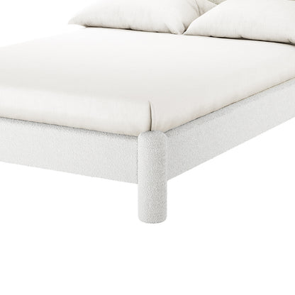 Close-up of the Rhoda Double Boucle Fabric Bed Frame in Cream White, showcasing its textured, rounded fabric frame and cylindrical leg, with a light-colored mattress and pillows visible.