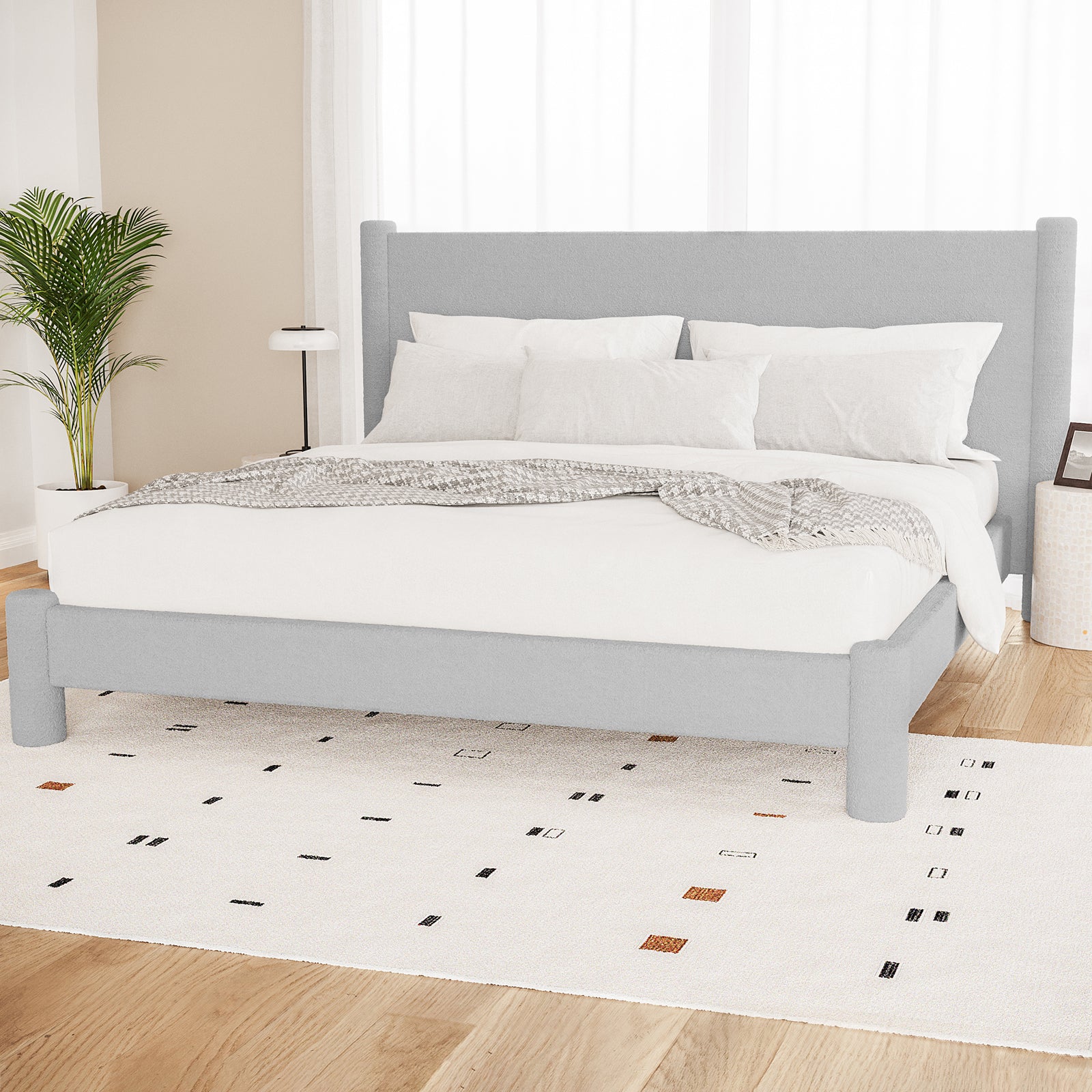 Rhoda King Boucle Fabric Bed Frame in Light Grey features a tall padded headboard, upholstered frame, white bedding, pale-grey throw, abstract rug, and minimalist decor in a serene bedroom setting.