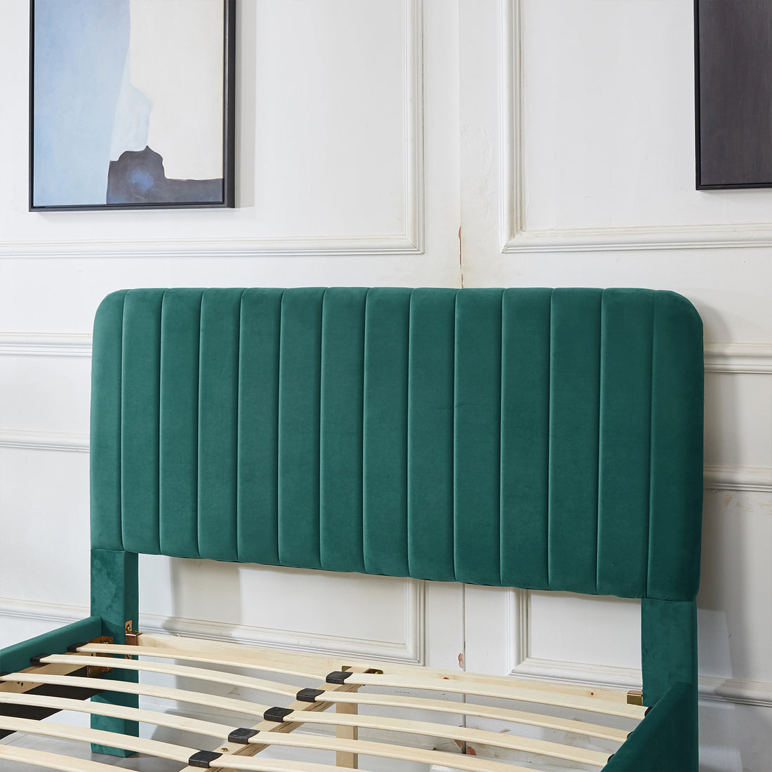 Seneca Upholstered Velvet Bed - Green Double with a tall, vertical-stitched headboard, partially assembled, showing wooden slats extending from the headboard, set against a white paneled wall.