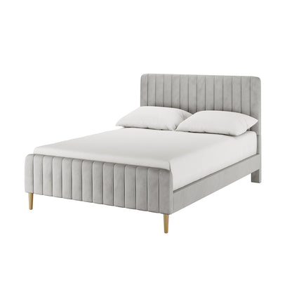 Seneca Double Upholstered Velvet Bed – Slate: Modern platform bed with light gray upholstered frame, channel-tufted headboard, matching footboard, wood-tone legs, white mattress, and pillows.