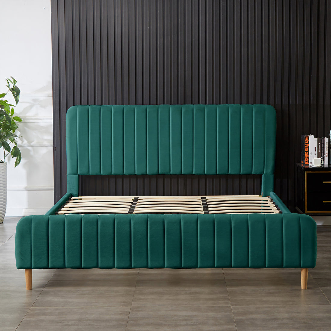 Seneca King Curved Velvet Fabric Bed Frame in Green, featuring a deep emerald-green velvet with channel-tufting on the headboard, slatted support, and light-wood legs against a ribbed accent wall.