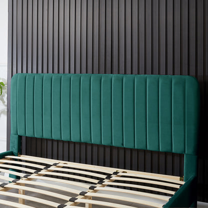 Seneca King Curved Velvet Fabric Bed Frame in Green, featuring an emerald-green vertically-channeled headboard, matching side rails, and flex-wood slats, partially assembled against a grooved wall with a potted plant nearby.