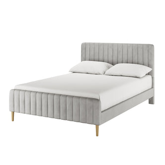 Seneca Queen Upholstered Velvet Bed – Slate, featuring a low-profile frame with vertically channel-stitched headboard and footboard in light gray fabric, resting on simple wooden legs with a mattress and pillows.
