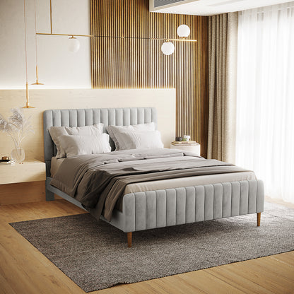 The Seneca Queen Upholstered Velvet Bed – Slate features a low-profile, channel-tufted design with neutral bedding, set against a vertical wood-slat accent wall with minimalist pendant lights.