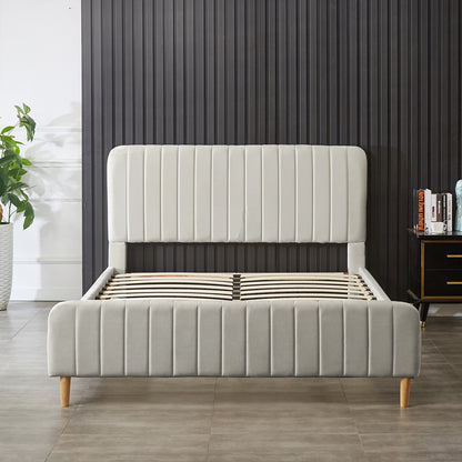 Seneca Queen Upholstered Velvet Bed – Slate: Modern platform bed with a tall, channeled headboard, light gray fabric, and wooden legs, featuring exposed slatted supports, adjacent to plant and bedside table.