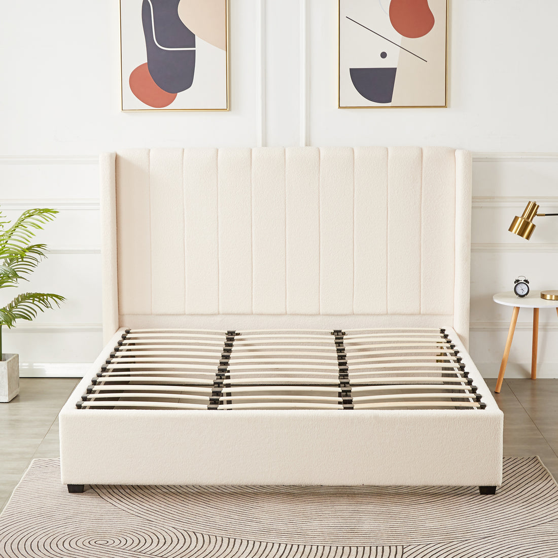 Septima & Fulvia Bouclé King Bed Base & Winged Headboard in Cream White features a tall, vertically-channeled headboard, exposed wooden slats, and complements minimalist decor with gold-framed art and a brass lamp.