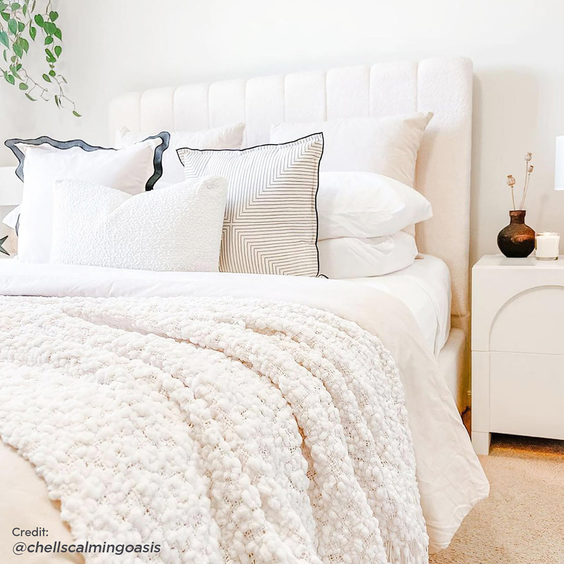 Septima & Gratiana Queen Bed Base & Headboard in Cream White features a channel-tufted bouclé headboard with decorative pillows, paired with a minimalist bedside table and cozy knit throw for an elegant bedroom setting.