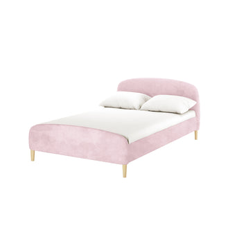 Theron Double Upholstered Velvet Bed in Light Pink features a modern, low-profile design with a blush-pink upholstered frame and headboard on light-wood legs, set against a white backdrop.