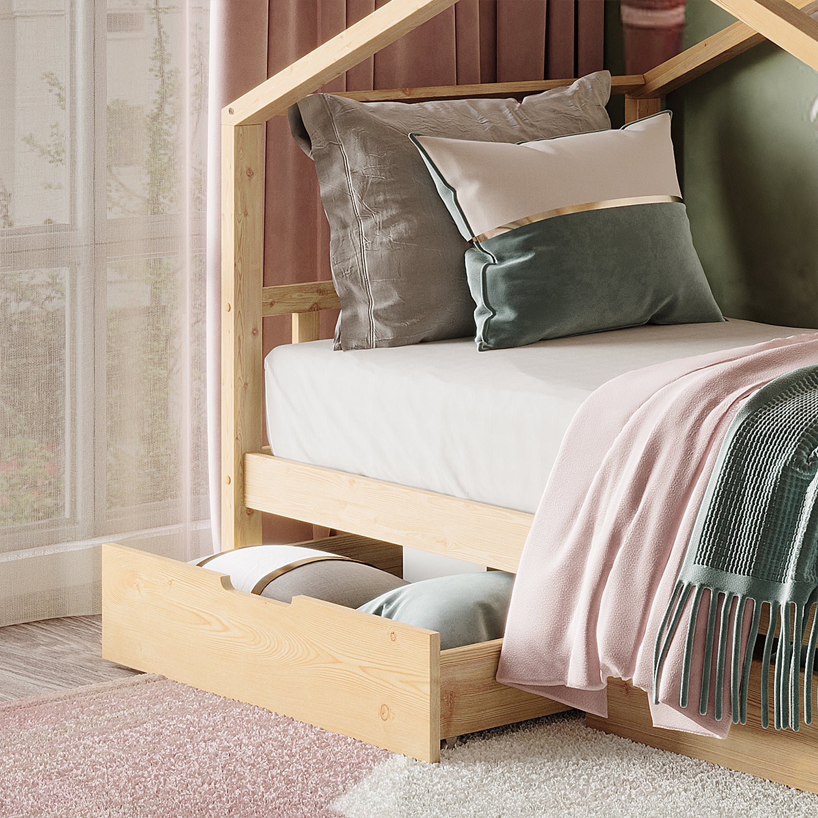 Tucker Solid Pine Timber Kids Bed with Drawers Natural features a house-shaped frame, layered pillows, a pink blanket, and green throw, with a pull-out storage drawer beneath, set in a cozy bedroom.